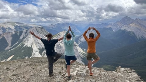 Three women doing yoga pose against snowy mountains