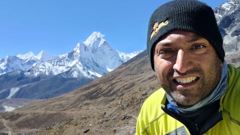 Dr. Dhillon smiling at camera in front of Mount Everest