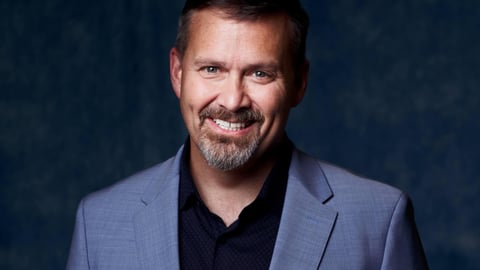 Man with glasses and a blue suit jacket