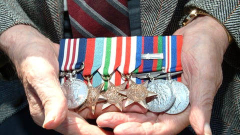 man-hands-shows-six-medals-with-ribbons