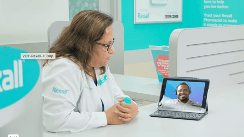 A woman in a white lab coat talks to a man in a video on an iPad  