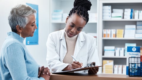 Pharmacy, Black female pharmacist with a customer, a woman of colour, helping explaining using clipboard.