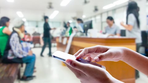 A person using a mobile phone inside a hospital waiting area.