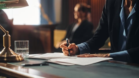 A woman in a suit signs legal documents