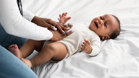 Young Black mother comforting her crying infant who has tummy trouble