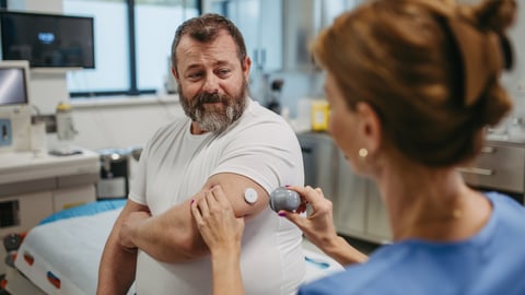 Doctor applying a continuous glucose monitor sensor on patient's arm.
