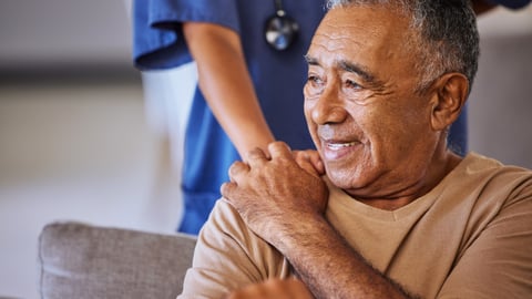 older black man holding hand of nurse or doctor with hand on his shoulder