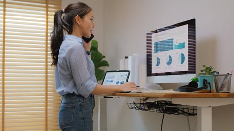 A woman uses a standing desk while working.