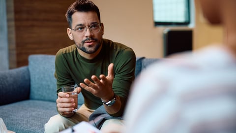 Young fair-skinned man with glasses chatting with a mental health professional