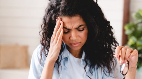 Dark-skinned woman holding her head in pain