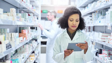 Young pharmacist examining a box of pills
