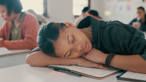 Older teenage girl sleeping on her desk at school