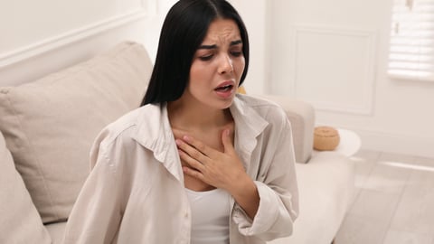 Young woman sitting on her bed struggling for breath