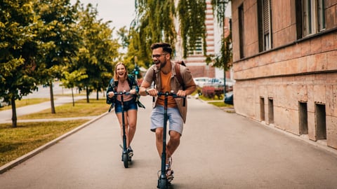 Young couple laughing as they ride e-scooters