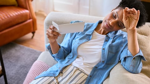 Woman experiencing a hot flash as she lies down on sofa