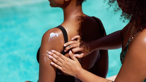A friend applying sunscreen to her friend's back