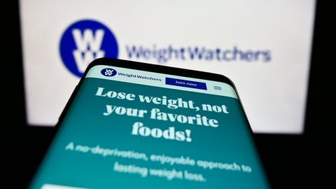 Smartphone with website of WW International Inc. (Weight Watchers) on screen in front of business logo.