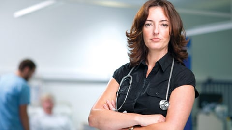 A woman doctor with her arms folded looking ahead sternly