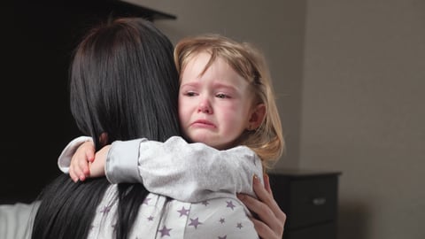 Young white girl crying in pain being held by her mother