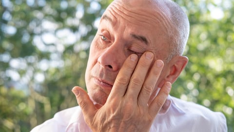 Older man rubbing his eye in discomfort