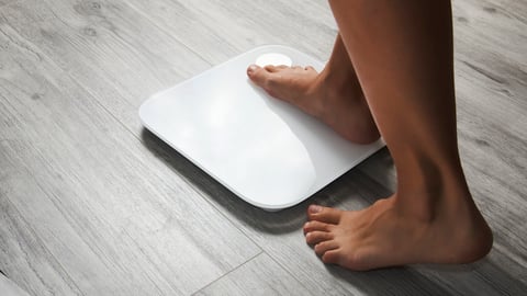 Female leg stepping on floor scales, close-up. Woman and weighing scales at home. Diet, healthy lifestyle, loss weight, slim concept.