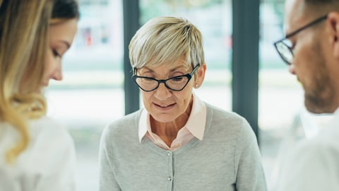 Older white woman with short white hair chatting with two pharmacy professionals