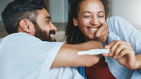 Happy couple celebrating a positive pregnancy test