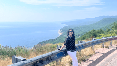 A woman leans against a guardrail on highway along Cabot Trail