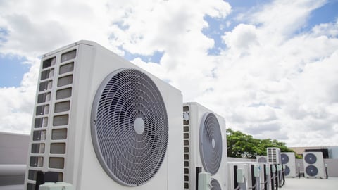 Air conditioning (HVAC) on the roof of an industrial building with blue sky and clouds.