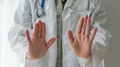 A doctor holds his hands up. 
