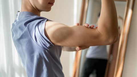 Young teen boy looking at his muscles in the mirror 