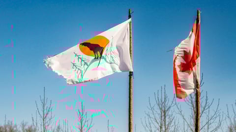 A frayed Attawapiskat First Nation Flag flies alongside a tattered Canadian flag in the isolated northern Ontario Indigenous community of Attawapiskat