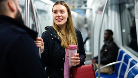 Young white woman on the subway chatting with a stranger