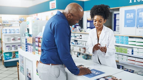 Pharmacist advising customer at pharmacy counter.