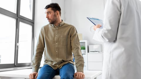 Youngish man looking out window getting bad news from doctor in white coat(1).jpg
