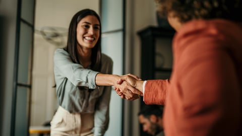 Young woman smiling, shaking the hand of the person interviewing her for a job