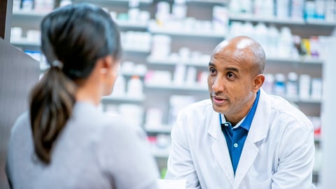 Middle-aged male pharmacist chatting with a patient