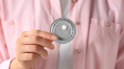 Woman holding a single wrapped emergency contraception pill