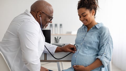 Smiling black pregnant woman visiting her obstetrician doctor in maternity clinic