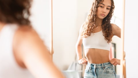 Older fit teen girl looking annoyed at herself in the mirror