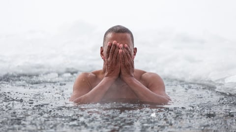 A man swims in an ice hole in the winter.