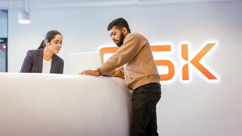 Two people working at a white desk.