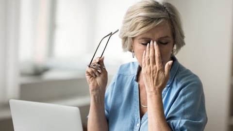 A senior white woman takes off her glasses and rubs her dry eyes