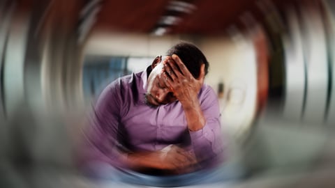 A young man sitting at a desk feeling extreme dizziness