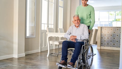 Older man in a wheelchair being looked after by his adult son