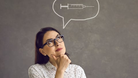 A woman in glasses looks questioningly at image of a vaccinatoin