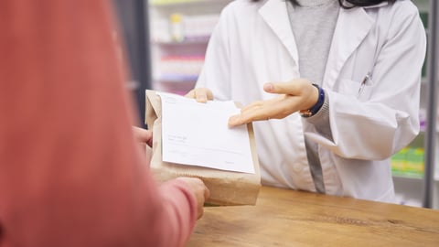 A pharmacist dispenses a drug to a patient.