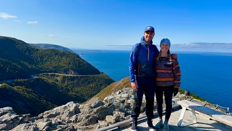 Two adults holding each other for a photo on a picturesque hiking trail