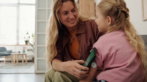 A woman helps a child with an insulin pump. 
