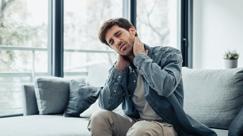 A man adjusts his neck while in pain. 